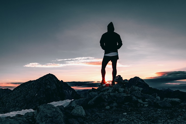 Hiker standing on top of mountains at sunset