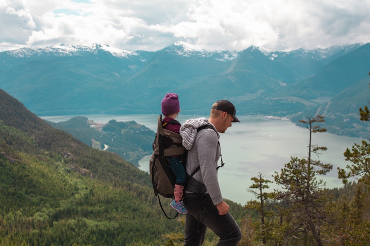 Father with his child on his back trekking in the mountains