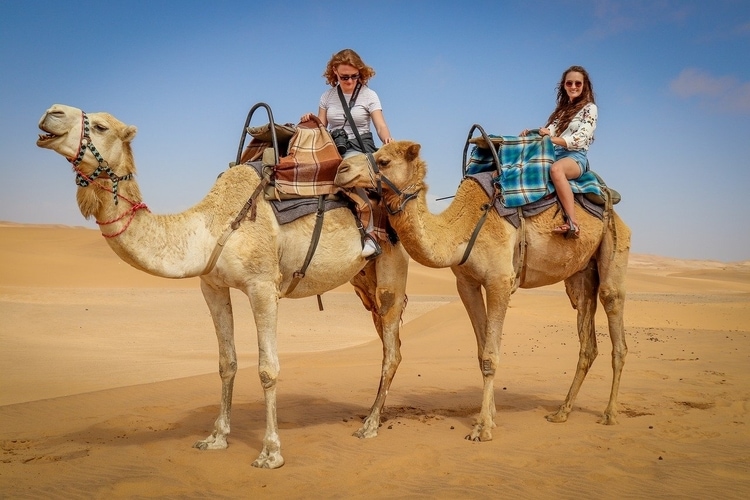 A couple riding a camel in the desert.